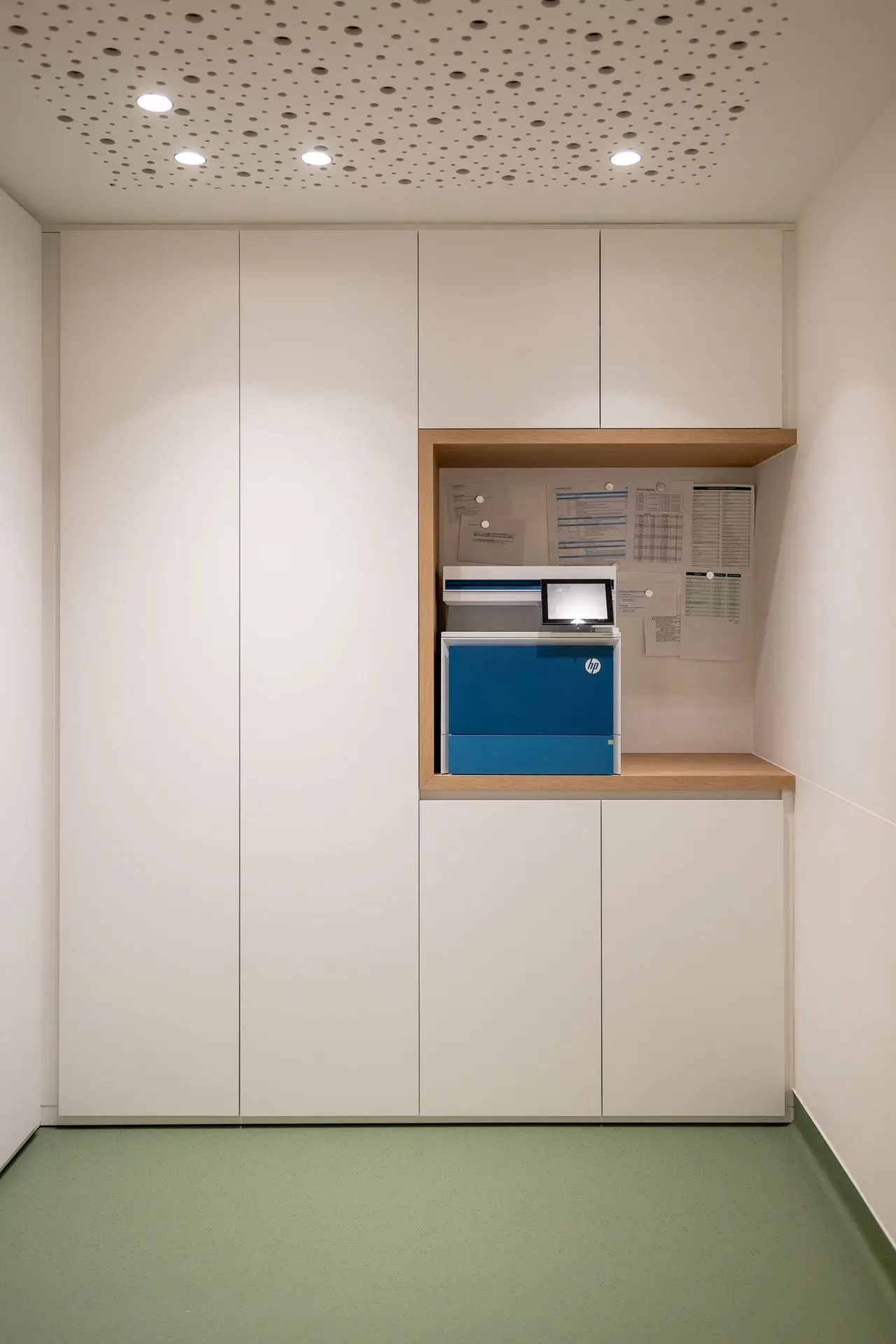Maatwerkkasten met geïntegreerde printerruimte en akoestisch plafond in de longartsenpraktijk van Sint-Truiden.