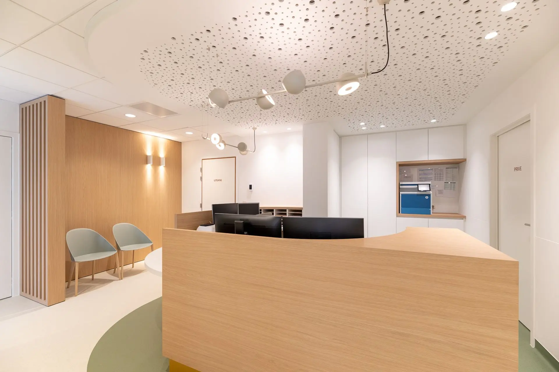 Ergonomisch onthaal met maatwerkbalie en akoestisch plafond in de vernieuwde longartsenpraktijk van Sint-Truiden.