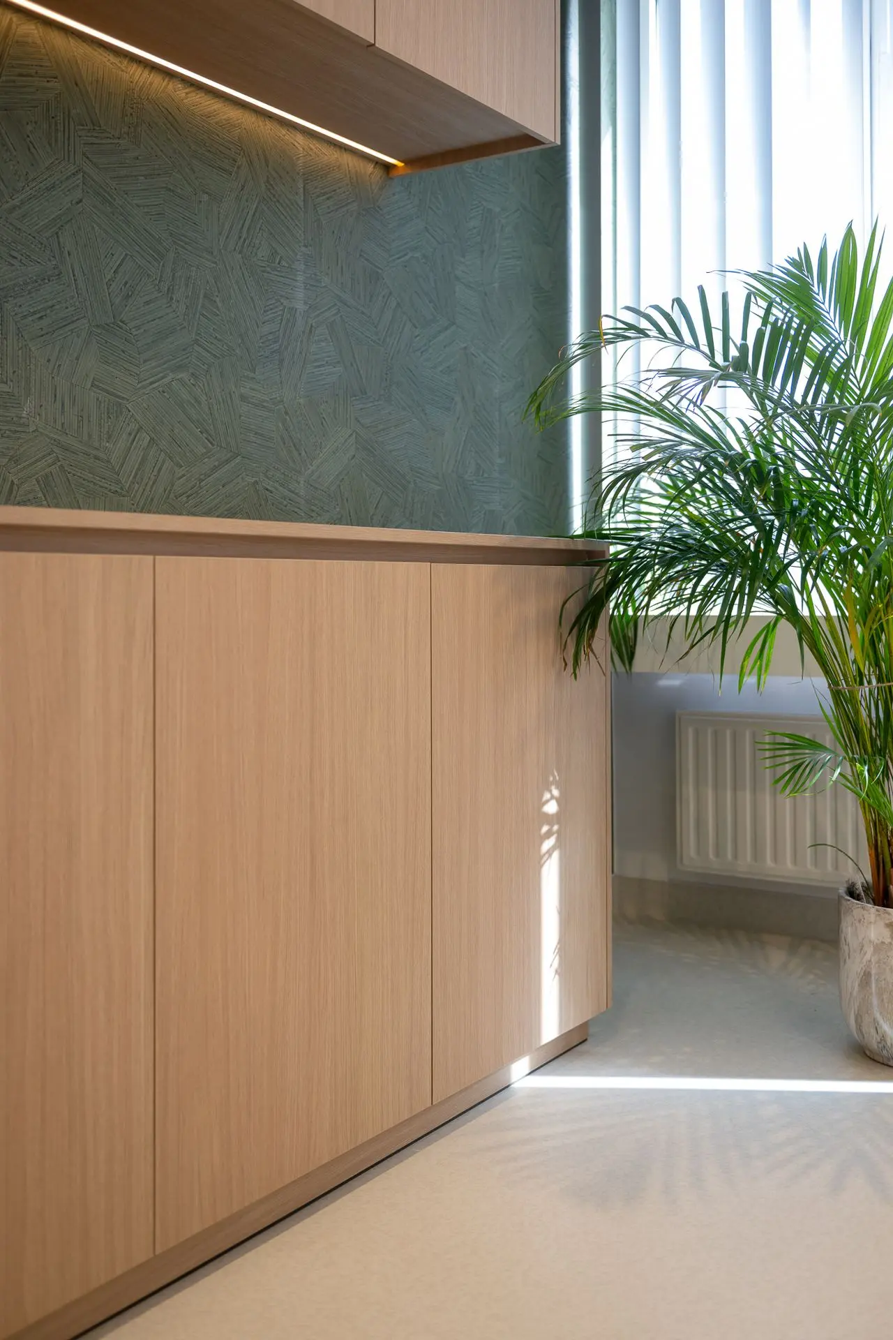 Maatwerkkasten met groene accentwand in de vernieuwde longartsenpraktijk in Sint-Truiden.