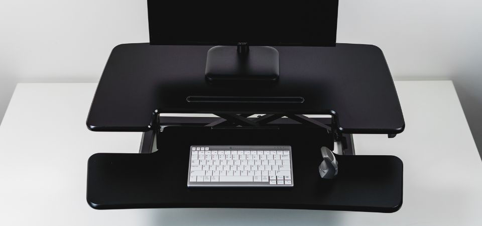 Detail van de zwarte Adjustable Sit-Stand Desk Riser 2 met twee niveaus, inclusief een DXT-muis en een UltraBoard 950 toetsenbord.